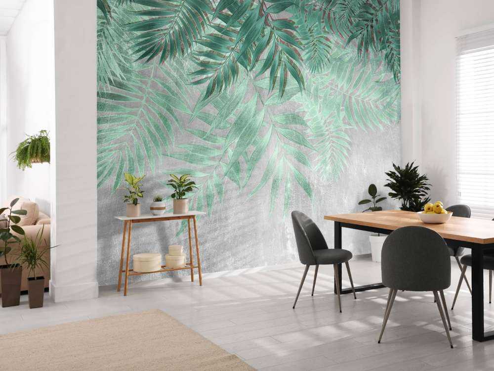 Feuilles de palmier vertes sur un mur en béton gris